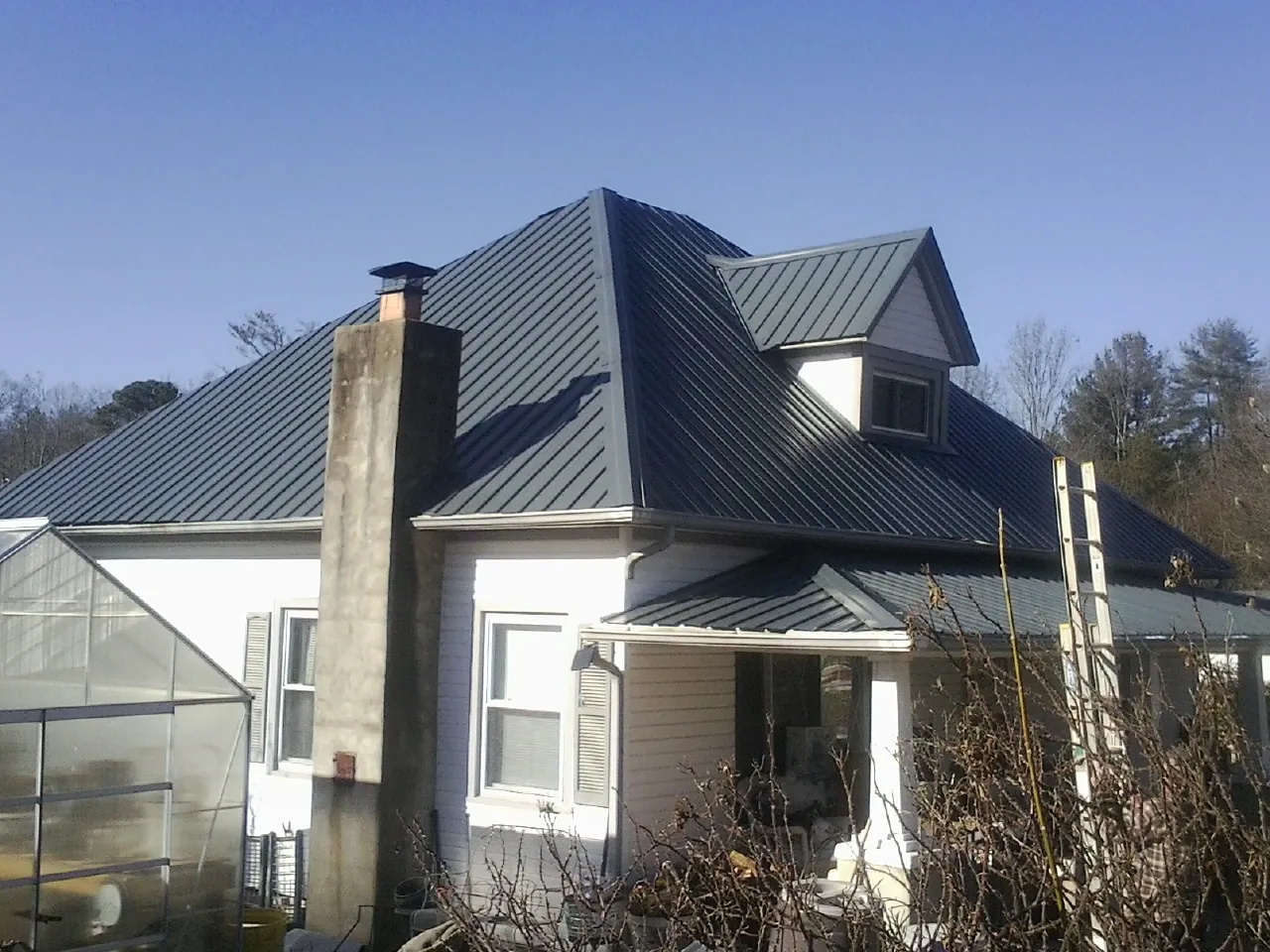 Dark blue standing seam metal roof on a white farmhouse with dormer — Slate & Tile Roof Repair by Roofing Brothers in Azusa
